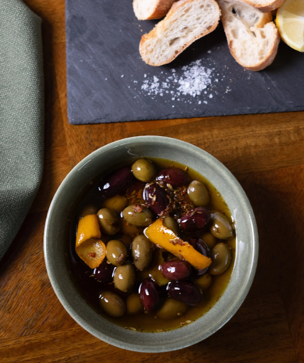 Just One More Olive recipe by Olivetta featuring mixed olives in extra virgin olive oil with citrus peel, herbs and spices, served with crusty bread and a napkin.